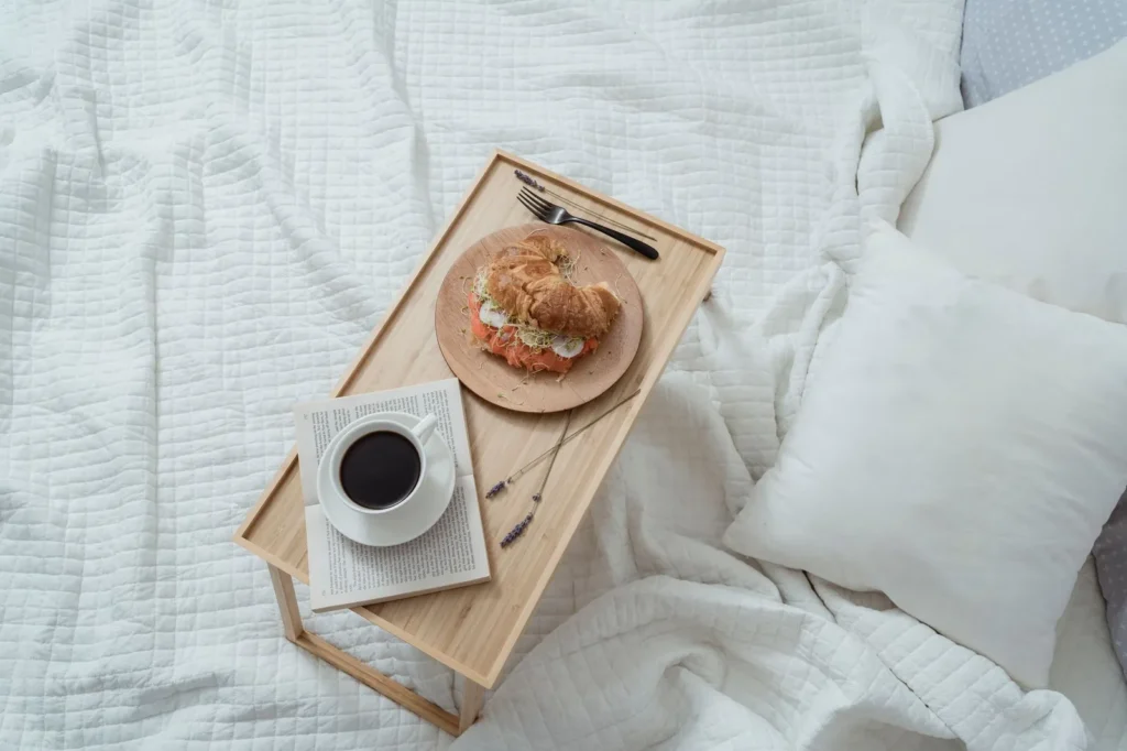 Ontbijt op bed met koffie en bloemen op witte lakens